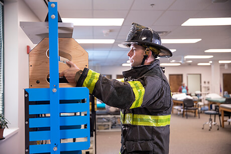 Male wearing firefighter uniform while performing occupational therapy exercises