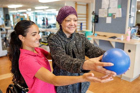 Therapist working with patient doing pain management exercises with a ball.