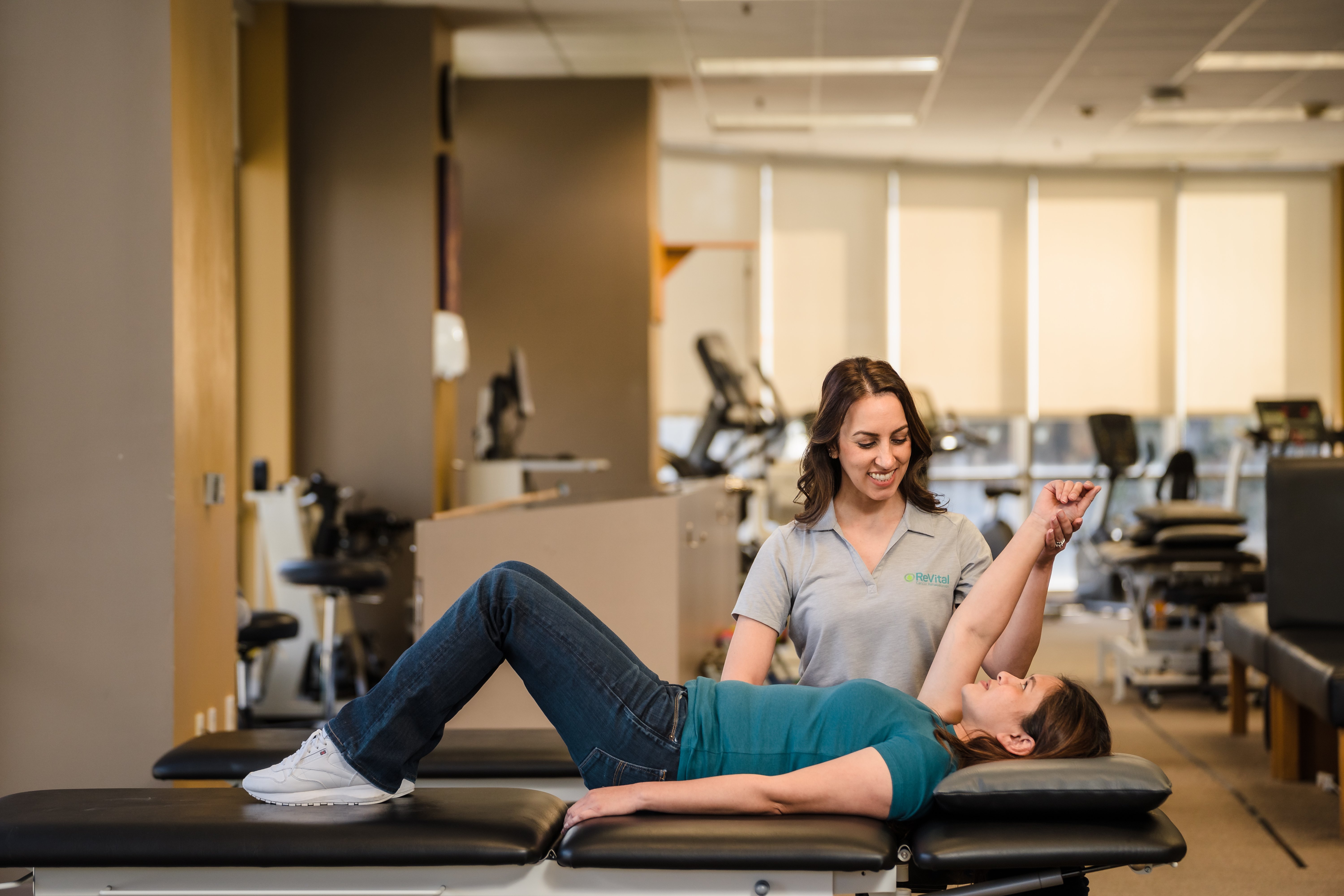 Physical therapist helps stretch a patient's arm while they lay on a table.