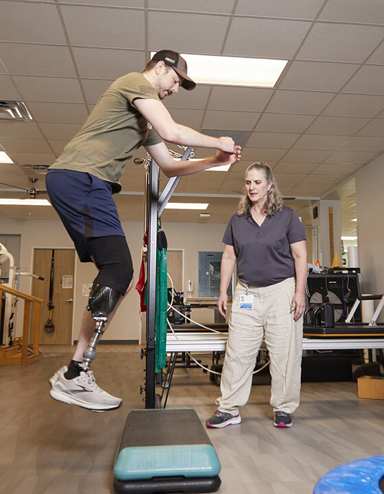 Amputee patient doing physical therapy, assisted by their therapist.