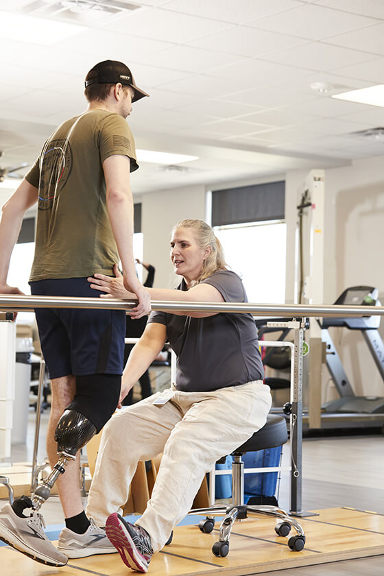 Amputee patient doing physical therapy, assisted by their therapist.
